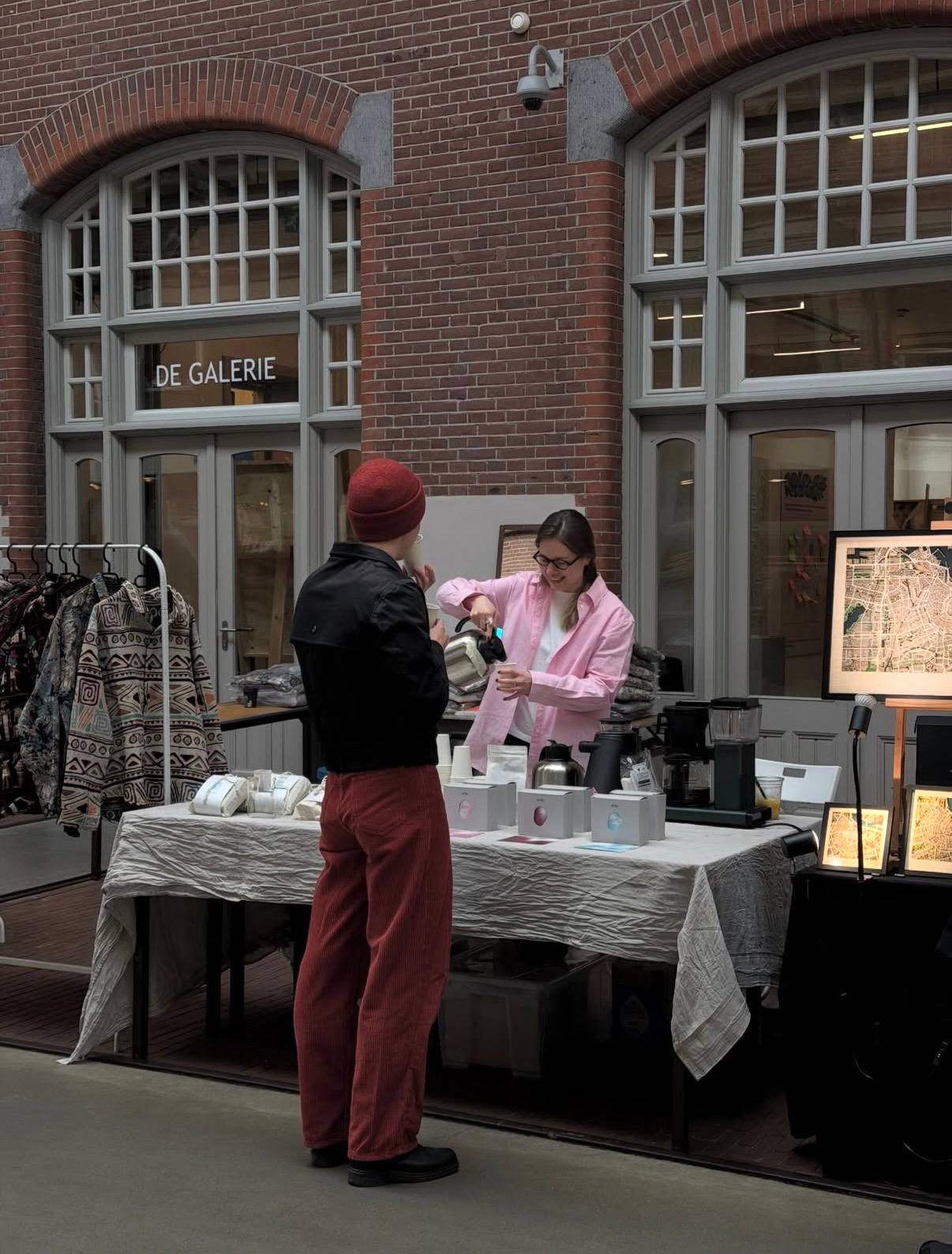 Koffie schenken voor een bezoeker bij de ATRI-stand in Foodhallen, Amsterdam.